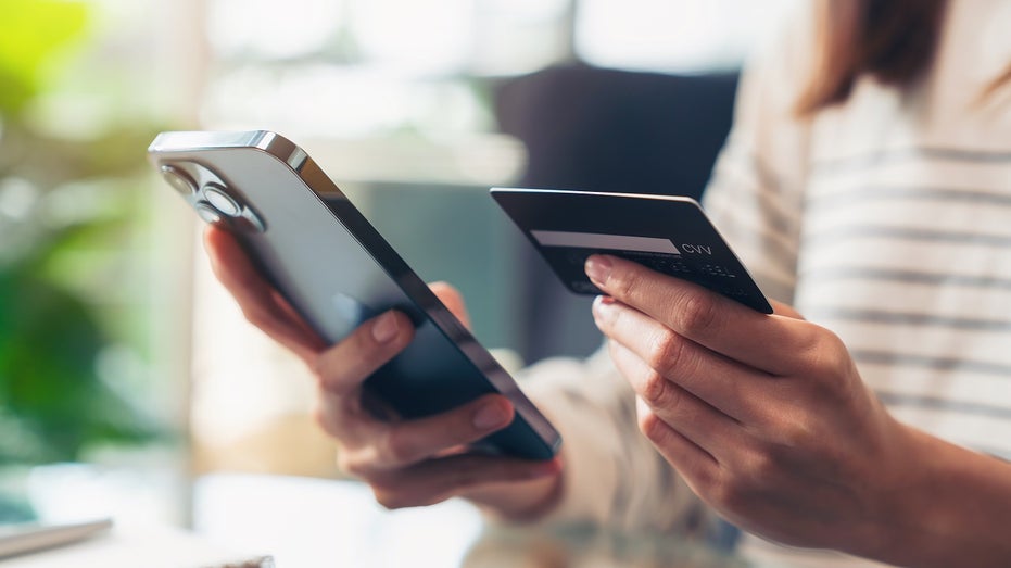 woman holding credit card and phone
