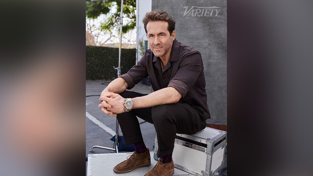 Ryan Reynolds posing for Variety magazine in a brown outfit.