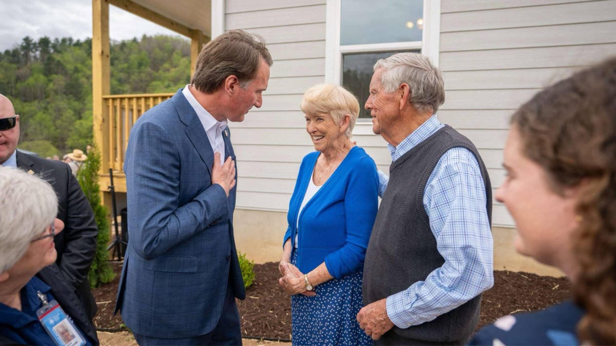 Gov. Glenn Youngkin, left, joins the couple for a ribbon-cutting ceremony for their new home after it was destroyed in Hurricane Helene.