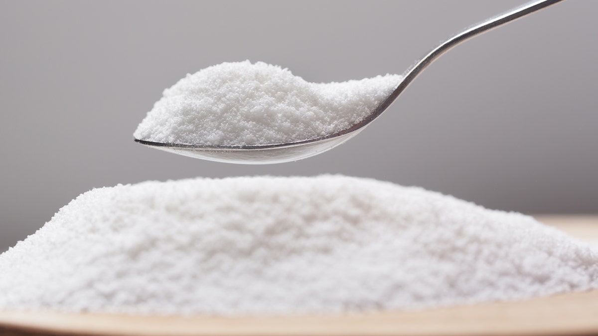 A spoon has a heap of sugar sweetener on it.